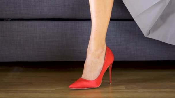 Femme sur le canapé en rouge talons hauts traverse sexy et slim longues jambes — Video