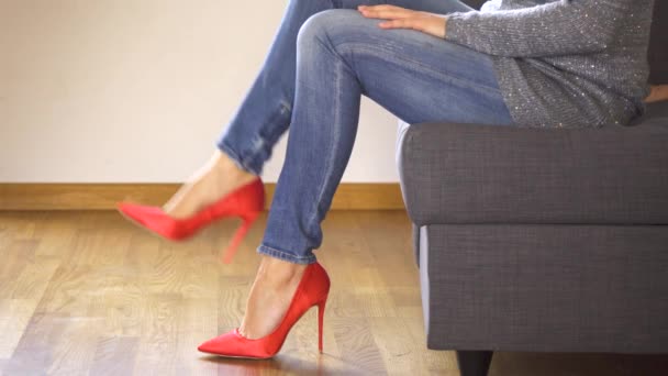 Nő a kanapén piros magas sarkú bemutatók és keresztek szexi és karcsú, hosszú lábak — Stock videók