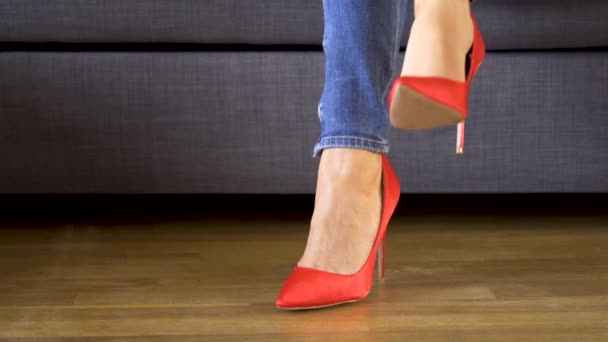 Žena na gauči v červených vysokých podpatcích ukazuje a kříží sexy a štíhlé dlouhé nohy — Stock video