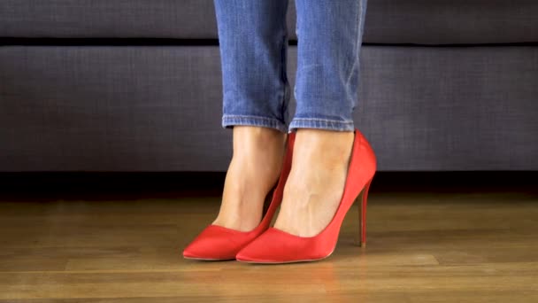 赤いハイヒールでソファの上の女性が表示され、セクシーでスリムな長い脚を横切ります — ストック動画