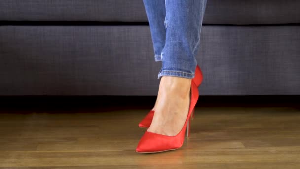Kırmızı yüksek topuklu kanepede kadın gösterir ve seksi ve ince uzun bacaklar haçlar — Stok video