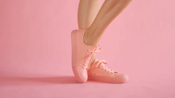 Close up of slim female legs dancing in sneakers on coral background — Stock Video