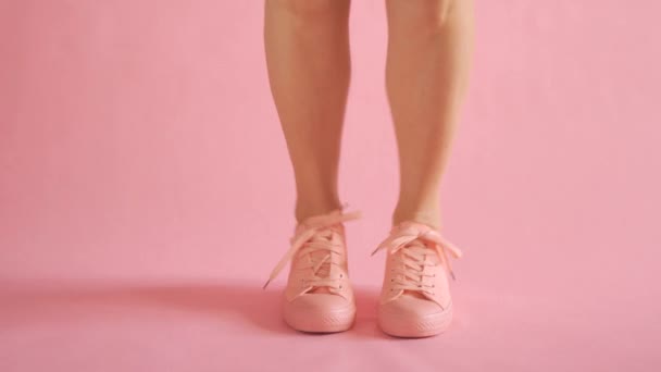 Blízkka štíhlých ženských nohou tančících v teniskách na korálovém pozadí — Stock video
