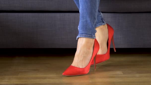 Mujer en el sofá en tacones altos rojos muestra y cruza sexy y delgado piernas largas — Vídeos de Stock