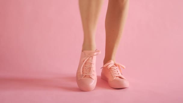 Close up of slim female legs dancing in sneakers on coral background — Stock Video