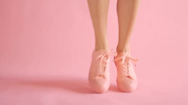 Acercamiento de piernas delgadas femeninas bailando en zapatillas de deporte sobre fondo de coral — Vídeos de Stock