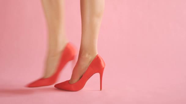 Close-up de pernas femininas bem torneadas andando em altos infernos sexy no fundo de coral — Vídeo de Stock