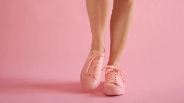 Крупный план стройных женских ног, танцующих в кроссовках на коралловом фоне — стоковое видео
