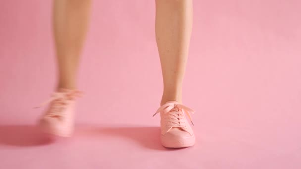 Close up de pernas femininas bem torneadas caminhando em tênis no fundo de coral — Vídeo de Stock