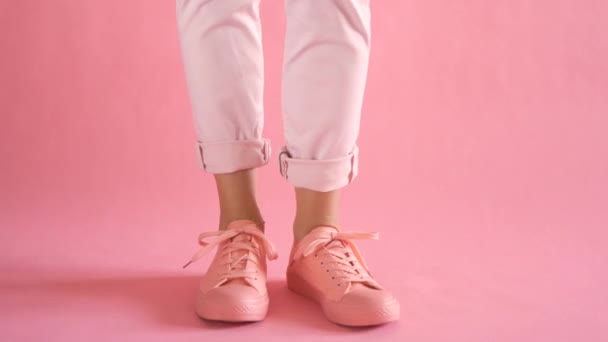 Close up of slim female legs dancing in sneakers on coral background — Stock Video