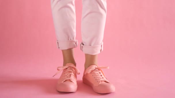 Acercamiento de piernas delgadas femeninas bailando en zapatillas de deporte sobre fondo de coral — Vídeo de stock