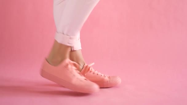 Close up of slim female legs dancing in sneakers on coral background — Stock Video