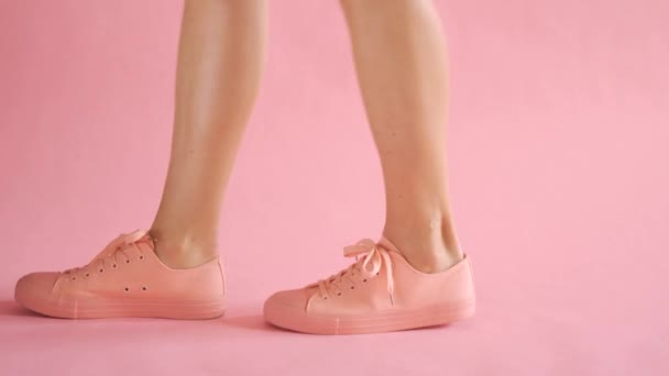 Close up of shapely female legs walking in sneakers on coral background — Stock Video