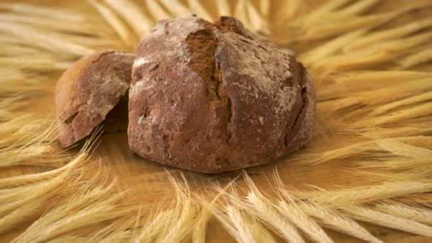 Tmavý domácí chléb s slunečnicovým osivem a žitným ušima na dřevěném stole — Stock video