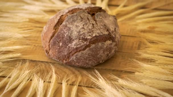 Dunkles hausgemachtes Brot mit Sonnenblumenkernen und Roggen-Ähren auf Holztisch — Stockvideo