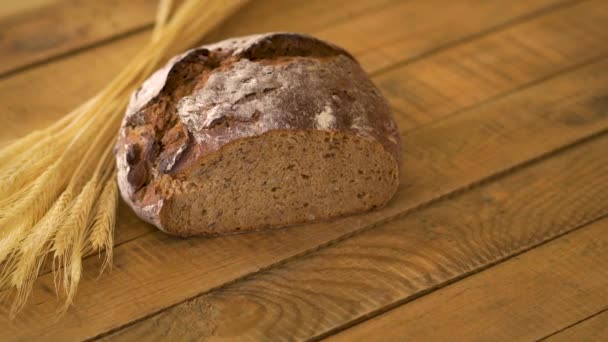 Donker zelfgebakken brood met zonnebloempitten en rogge oren op houten tafel — Stockvideo