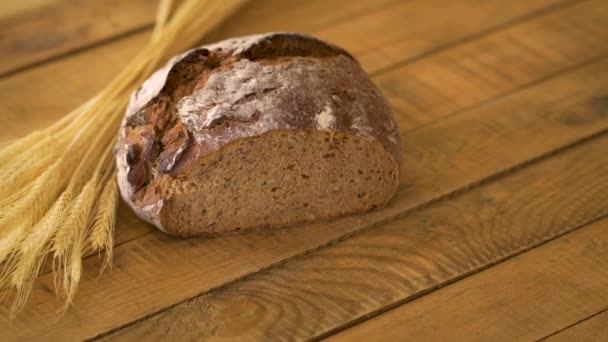 Dunkles hausgemachtes Brot mit Sonnenblumenkernen und Roggen-Ähren auf Holztisch — Stockvideo