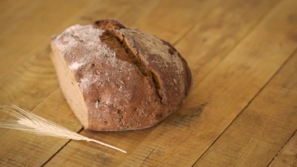 Dunkles hausgemachtes Brot mit Sonnenblumenkernen und Roggen-Ähren auf Holztisch — Stockvideo