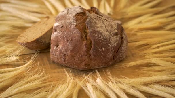 木のテーブルの上のヒマワリの種とライ麦耳を持つ暗い自家製パン — ストック動画
