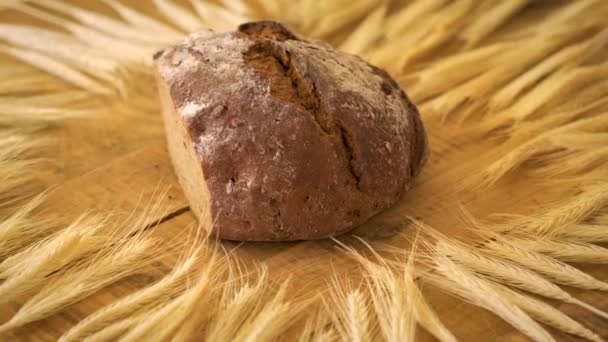 Dunkles hausgemachtes Brot mit Sonnenblumenkernen und Roggen-Ähren auf Holztisch — Stockvideo