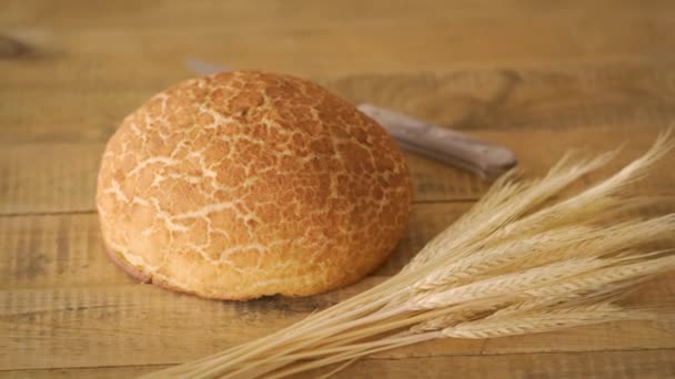 Pan de maíz casero dorado y cuchillo de madera y espigas de centeno en mesa de madera — Vídeos de Stock