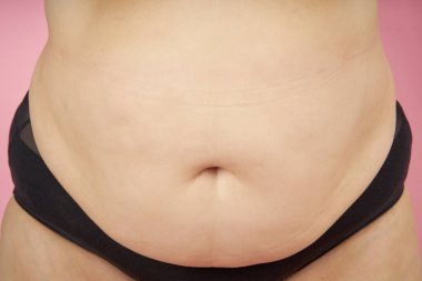Fat belly ve kilolu mercan arka plan üzerinde iç çamaşırı ile üst düzey kadın