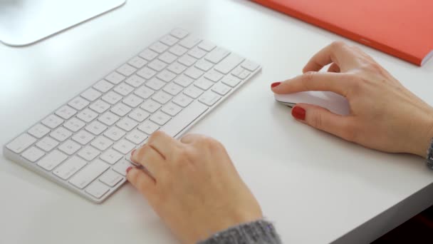 Las manos femeninas usan el ratón y escriben en el teclado blanco de la computadora — Vídeos de Stock