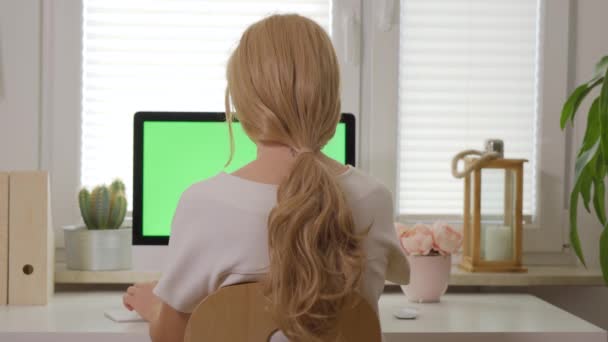 Πίσω όψη του γυναίκα που εργάζεται στο πληκτρολόγιο του υπολογιστή μπροστά από την οθόνη με απομονωμένες πράσινη οθόνη — Αρχείο Βίντεο