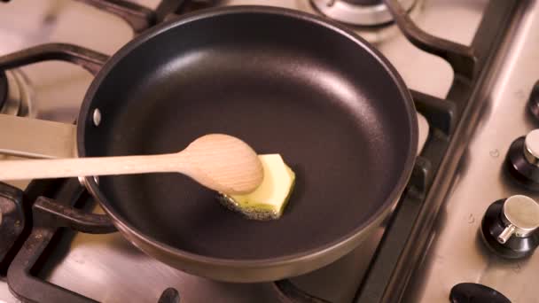 Vrouwelijke huis chef-kok smelt boter in een braadpan op het gasfornuis in de keuken — Stockvideo