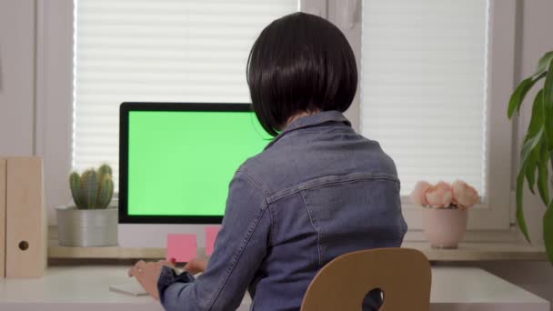 Vista posterior de la mujer que trabaja en el teclado de la computadora delante de la pantalla con pantalla verde aislada — Vídeo de stock