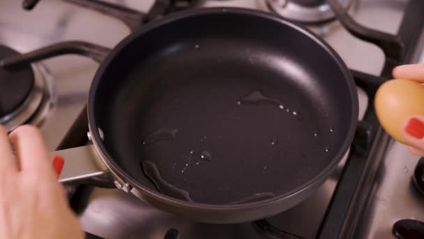 Mulher derrama e aquece o óleo de garrafa de vidro em panela de pé no fogão a gás — Vídeo de Stock