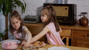 iki küçük kız bir krem koymak ve ahşap bir masada lezzetli cupcakes süslemeleri