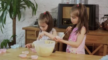 iki küçük kız cupcakes yapmak için kalıpları krem koymak
