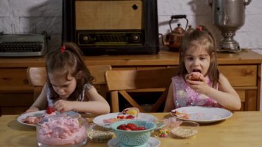 iki küçük kız bir krem koymak ve ahşap bir masada lezzetli cupcakes süslemeleri