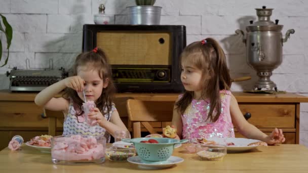Iki küçük kız bir krem koymak ve ahşap bir masada lezzetli cupcakes süslemeleri — Stok video