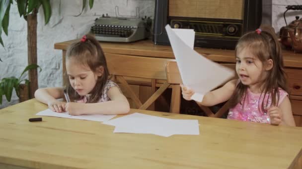 Zwei kleine Mädchen lachen und zeichnen an einem Holztisch — Stockvideo