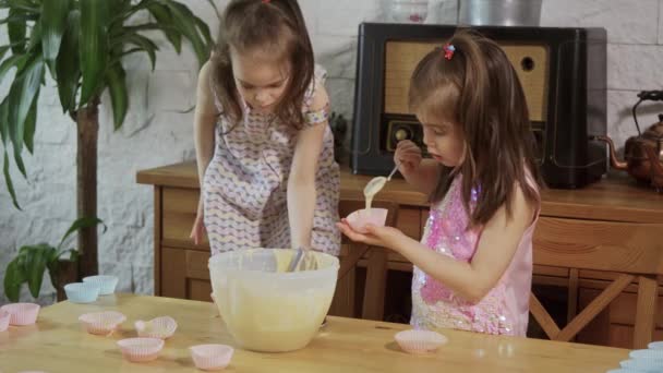 Zwei kleine Mädchen cremen die Formen ein, um Cupcakes zu machen — Stockvideo