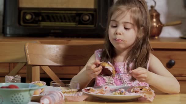 Petite fille décore et mange de délicieux petits gâteaux — Video