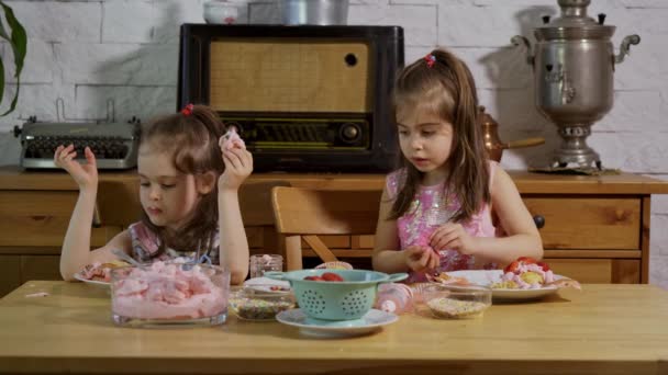 Dvě malé holčičky na dřevěném stole zdobila krémová jídla a zdobí lahodné koláčky — Stock video