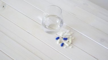 Kristal su cam ve beyaz ahşap masa üzerinde hap seti