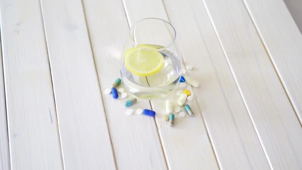 玻璃水晶水与柠檬和一套药片在白色的木桌上 — 图库视频影像