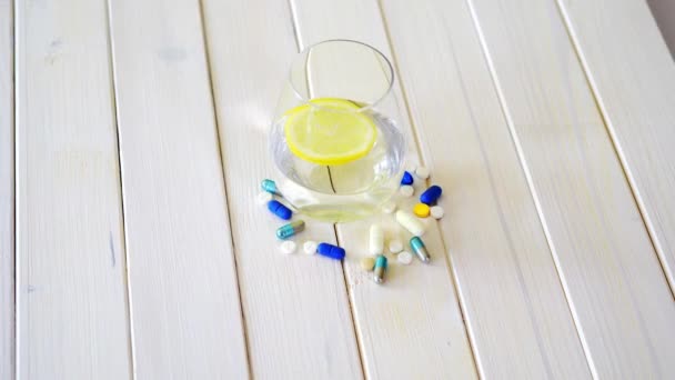 레몬과 흰색 나무 테이블에 알약 세트 와 크리스탈 물 유리 — 비디오