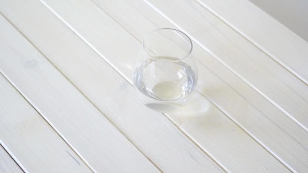 Bicchiere con acqua cristallina su tavolo di legno bianco — Video Stock