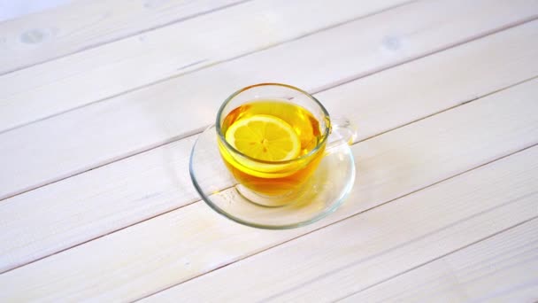 Стеклянная чашка с традиционным китайским чаем и ломтиком лимона на белом столе . — стоковое видео