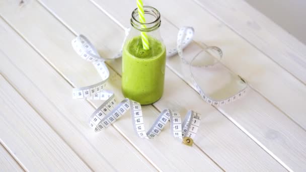 Gezonde groene en veganistische cocktail met centimeter tape op witte houten tafel — Stockvideo