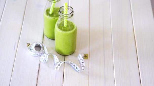 Gezonde groene en veganistische cocktails met centimeter tape op witte houten tafel — Stockvideo