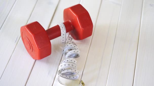 Rote Fitness-Hantel und Zentimeterband auf weißem Holztisch — Stockvideo