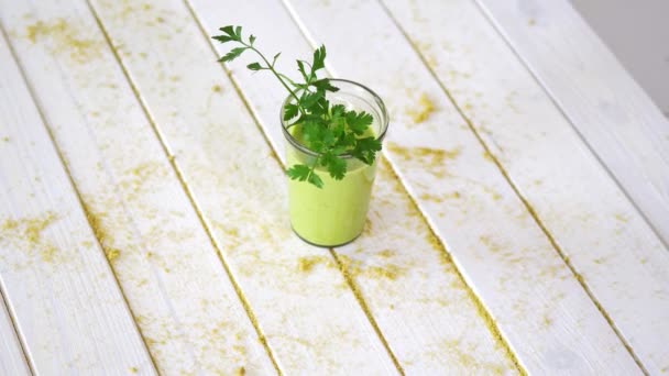 Gezond groen fruit en Vegan cocktail met takje peterselie op witte houten tafel met zand — Stockvideo