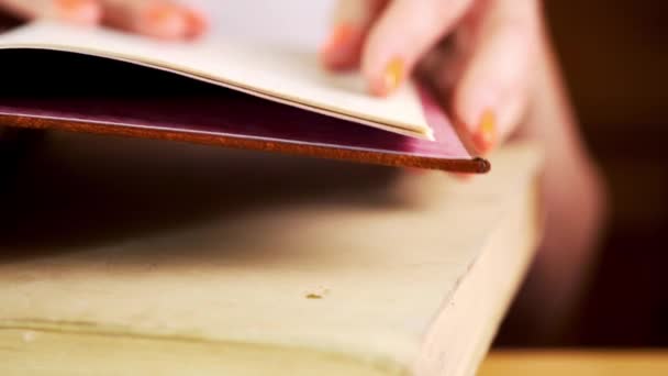 Vue d'une main de femme lisant un vieux livre sur une table — Video