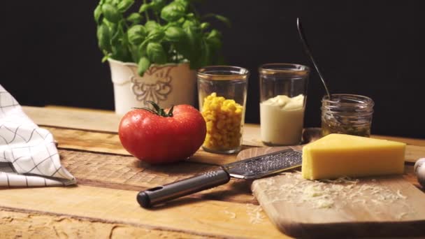 Queso rallado con albahaca fresca y jugoso tomate en mesa de cocina de madera — Vídeos de Stock
